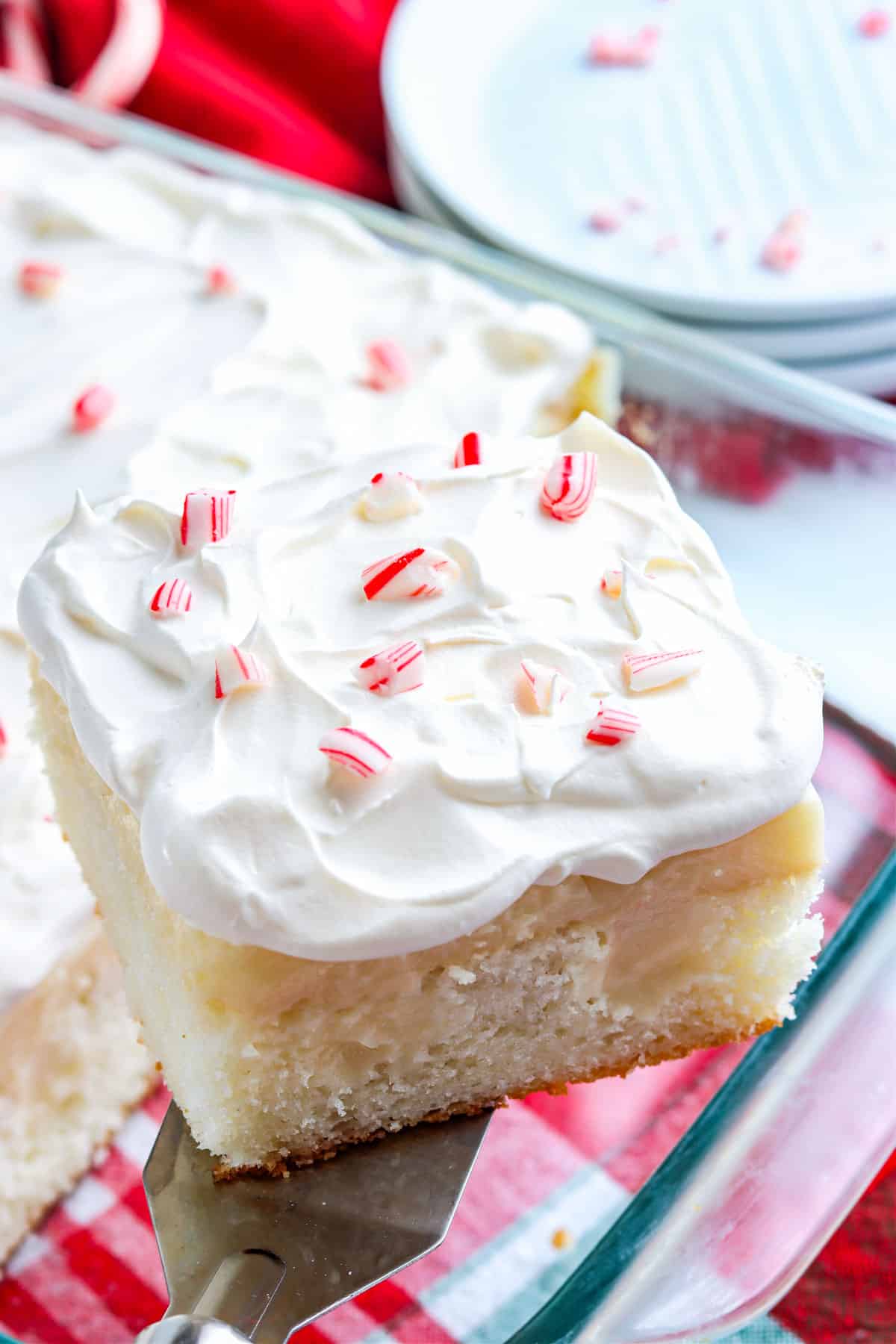 A piece of White Chocolate Peppermint Poke Cake being taken out of the pan. 