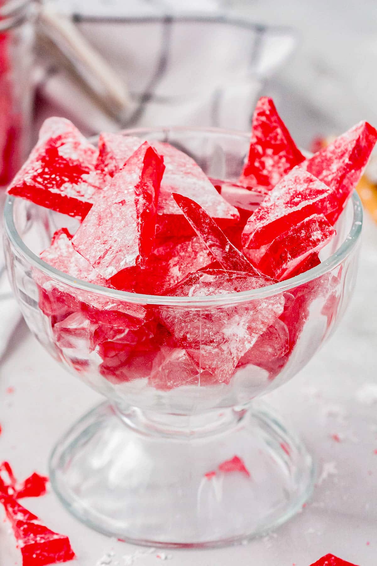 A glass bowl with pieces of cinnamon hard candy in it.