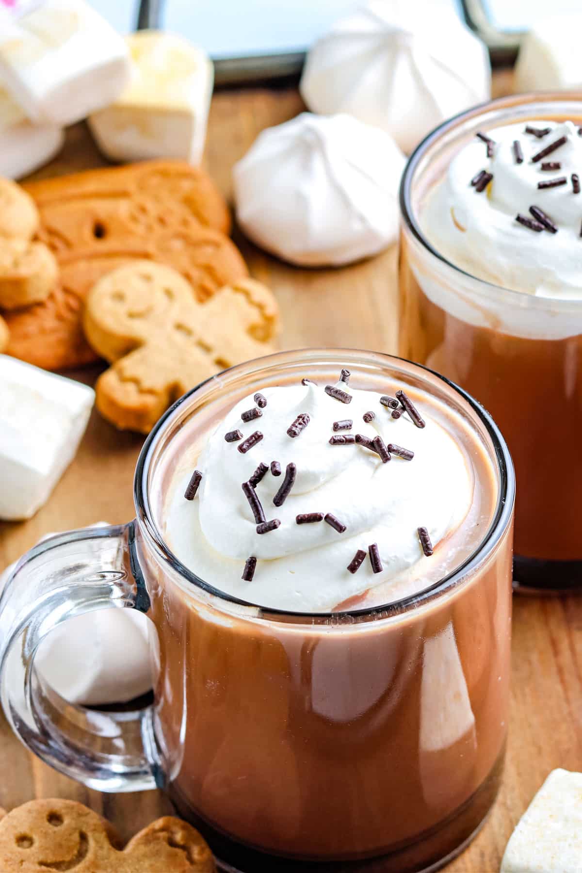 Gingerbread Hot Chocolate in mugs garnished with whipped cream and sprinkles. 