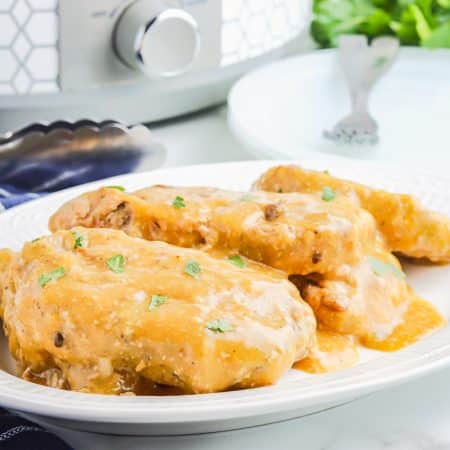 Two of the finished slow cooker ranch pork chops on a white plate.