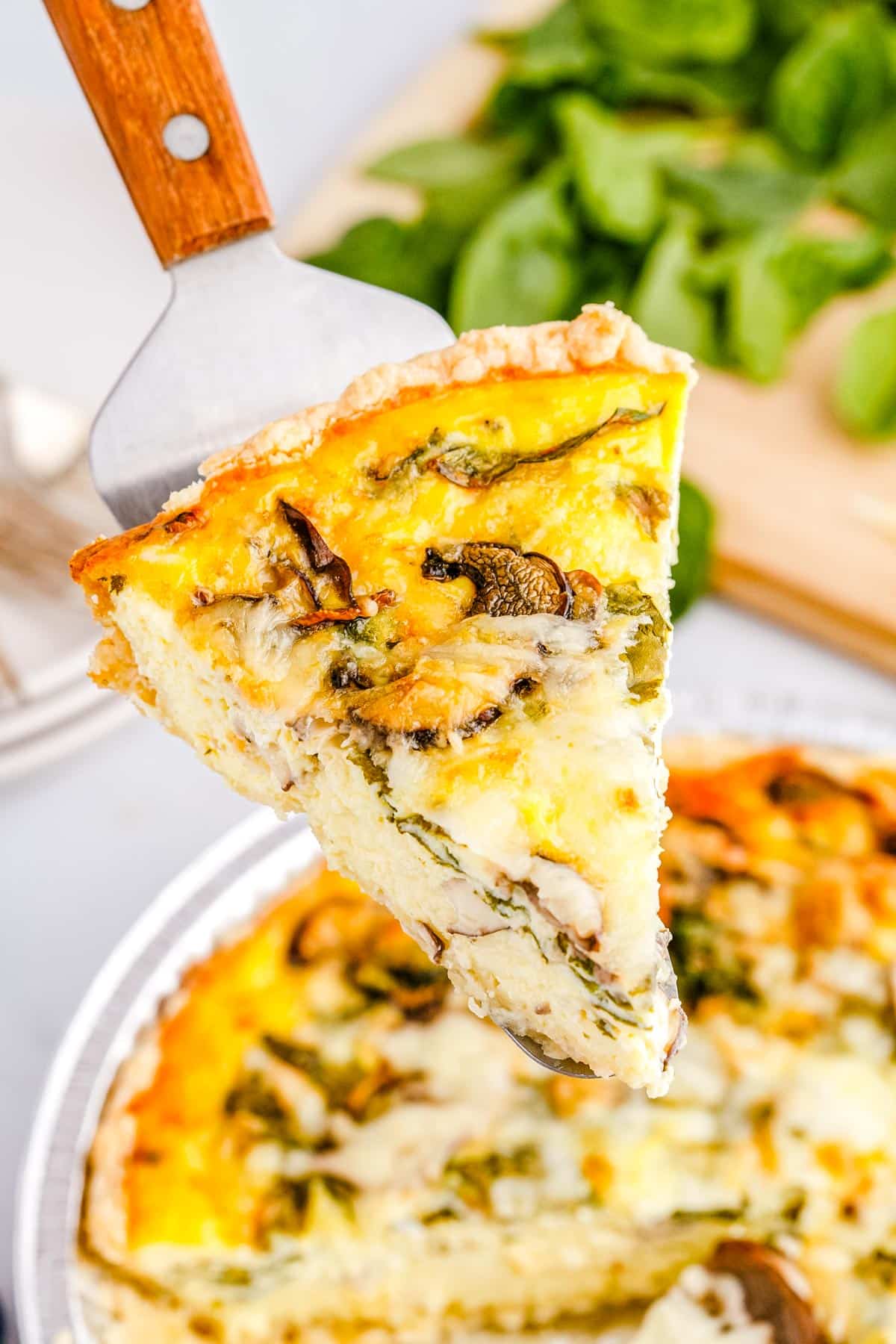 A slice of the spinach and mushroom quiche taken out of the larger quiche.