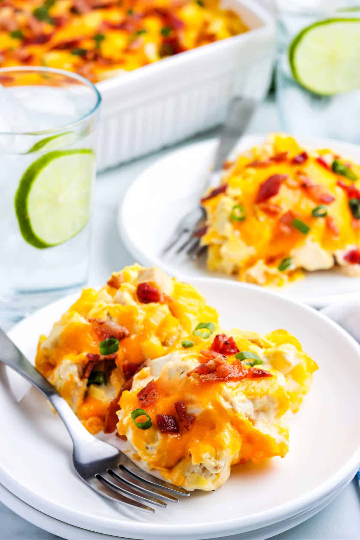 a slice of chicken potato casserole on a plate with another plate and the serving dish in the background