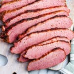 A close up of slices of corned beef smoked meat on a cutting board.