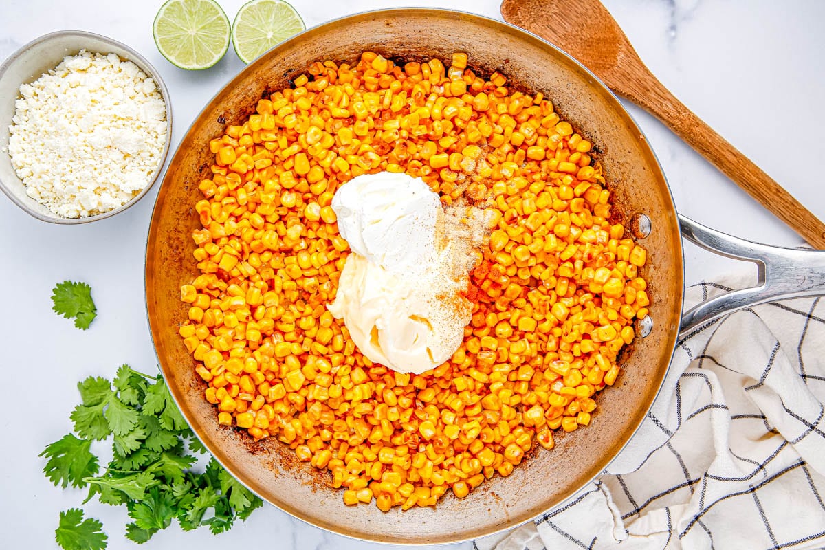 Mayo being mixing into the corn.