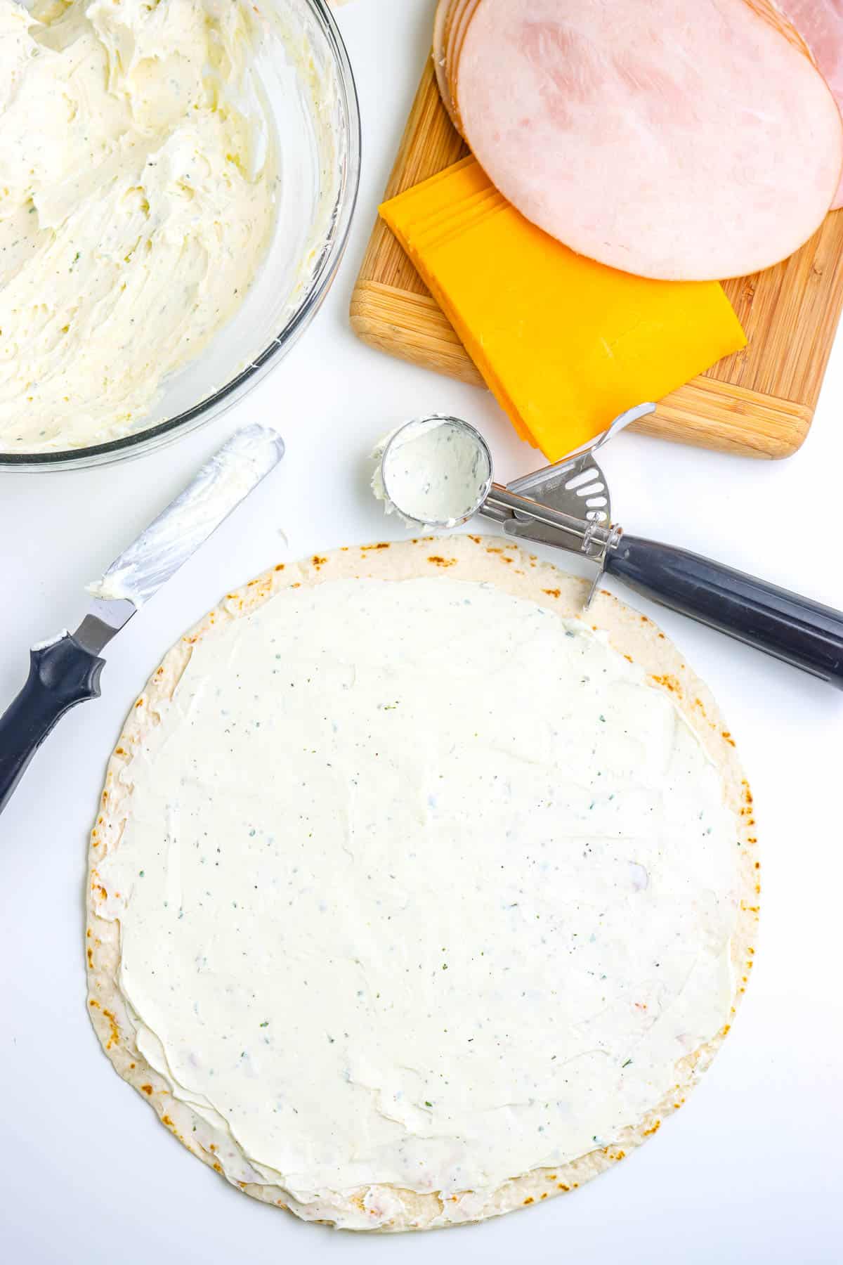 The cream cheese mixture spread evenly over a tortilla.