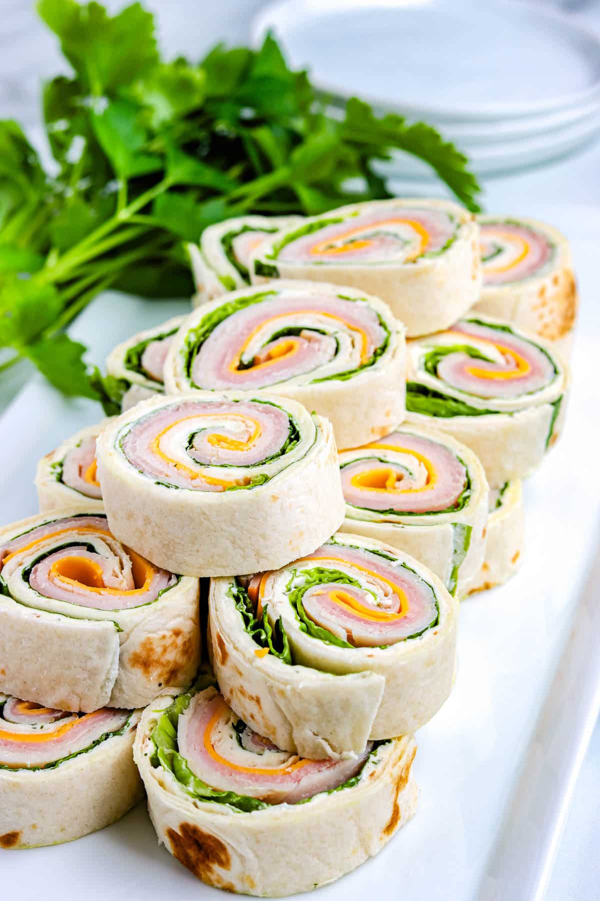 A stack of Pinwheels Sandwiches on a white platter.