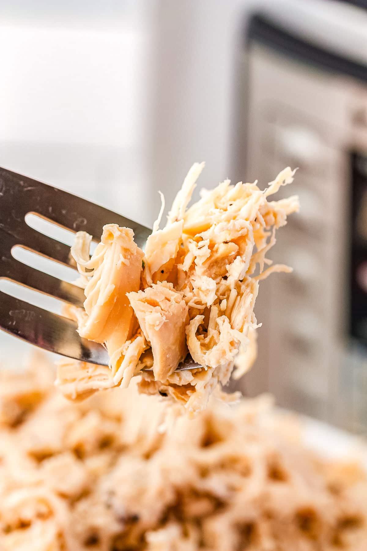 a fork taking a bite from a bowl of shredded chicken