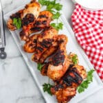Grilled chicken drumsticks on a white platter.