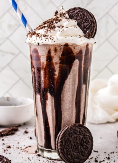 A copycat Chick Fil A Oreo milkshake in a glass and garnished with whipped cream and Oreo crumbs.