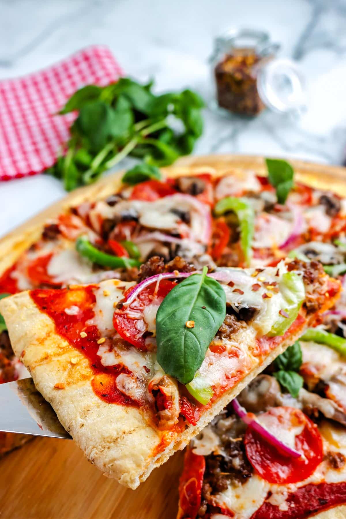 A slice of pizza being lifted from the pizza peel.