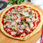 A grilled pizza on a wooden pizza peel.