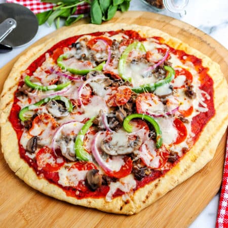 A grilled pizza on a wooden pizza peel.