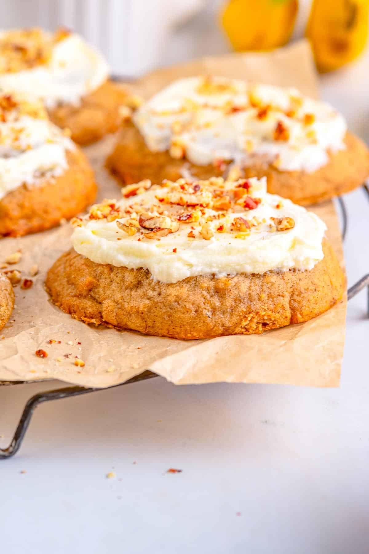 A soft and chewy banana cookie topped with cream cheese frosting and nuts.