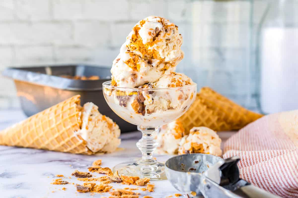 Scoops of ice cream in a serving dish with an ice cream scoop layed next to it.