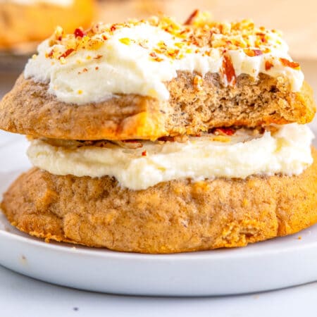 Two cookies stacked on top of each other with a bite taken out of the top one.