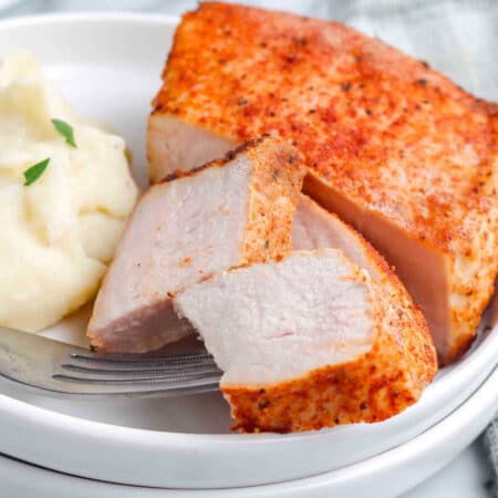 Boneless pork chops on a plate and some piece cut off so you can see what the inside looks like.