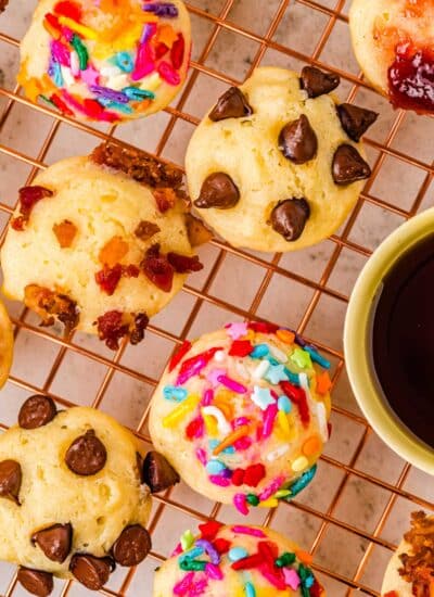 Pancake bits with various toppings like bacon, chocolate chips, jam, and cereal on a wire rack.