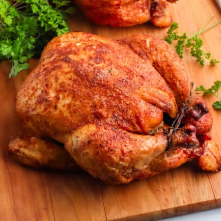 A Smoked Whole Chicken on a wooden cutting board.