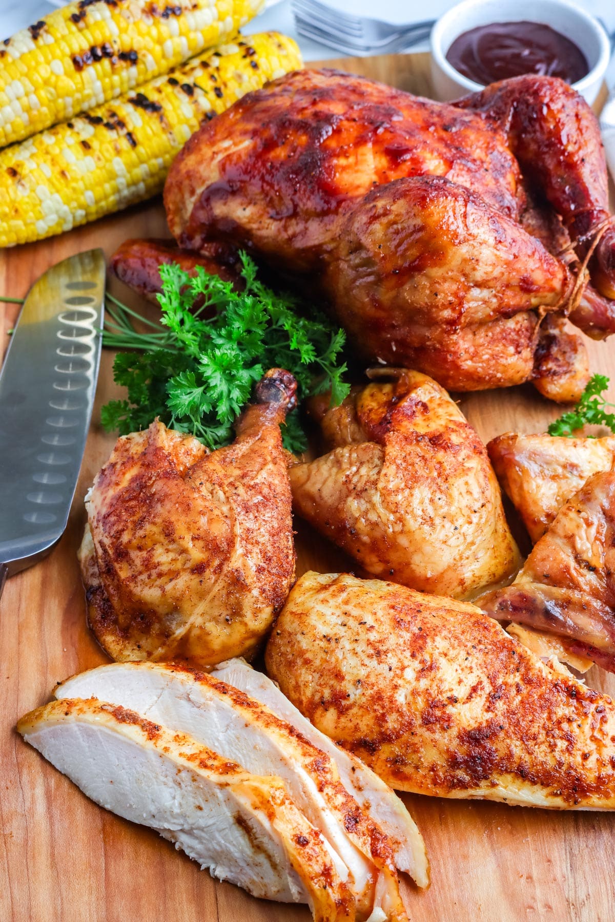 A whole chicken cut into pieces with another chicken in the background.