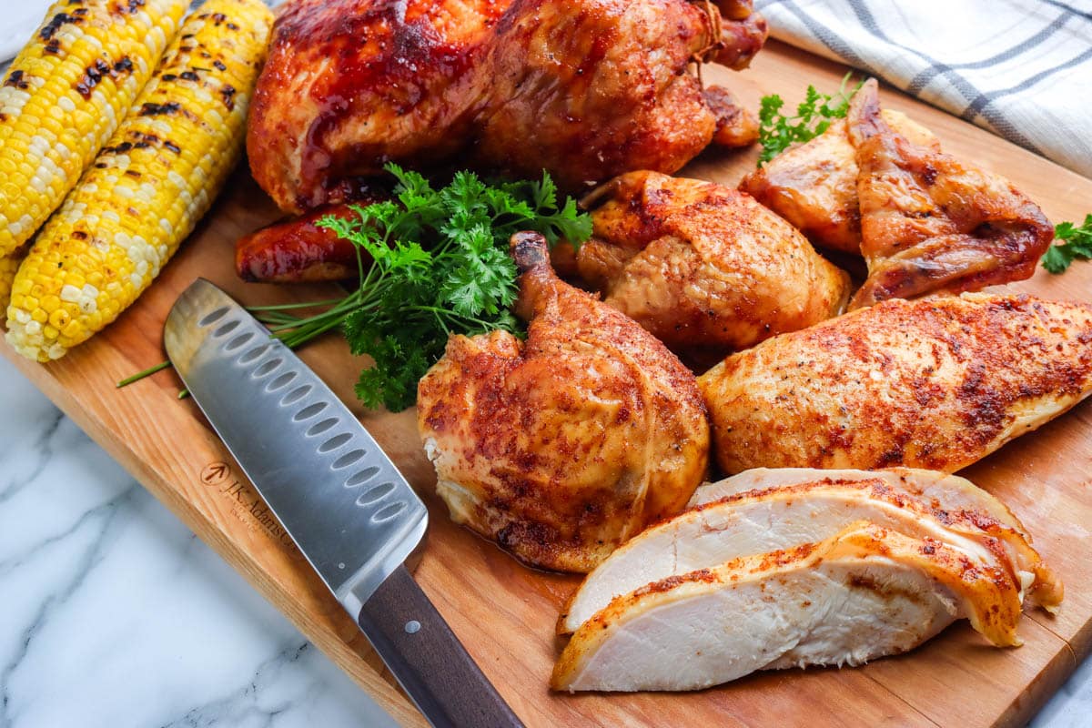 Cut pieces of the whole chicken on a wooden cutting board.