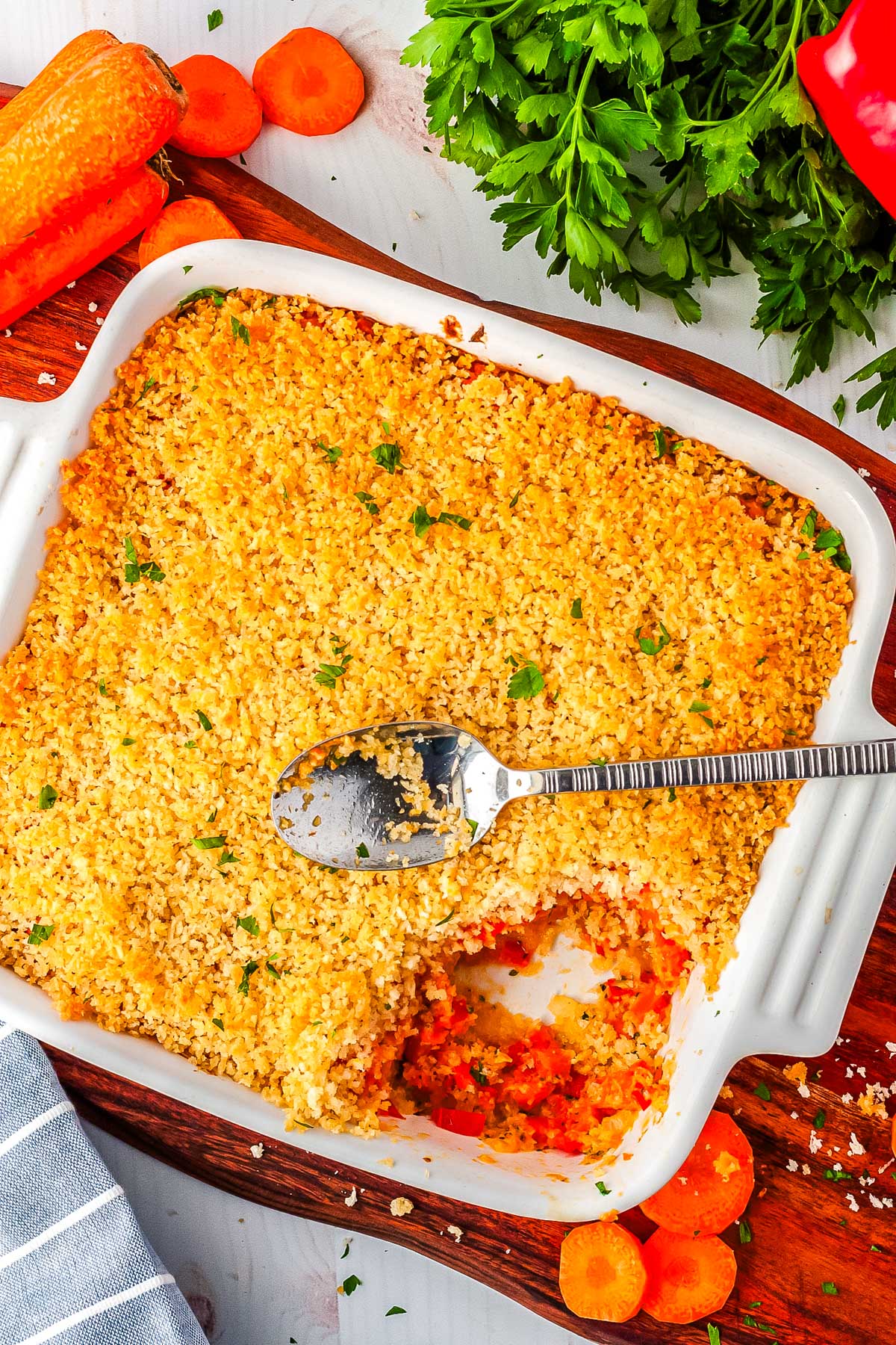 The finished carrot casserole in a baking dish with a serving spoon resting on the top.