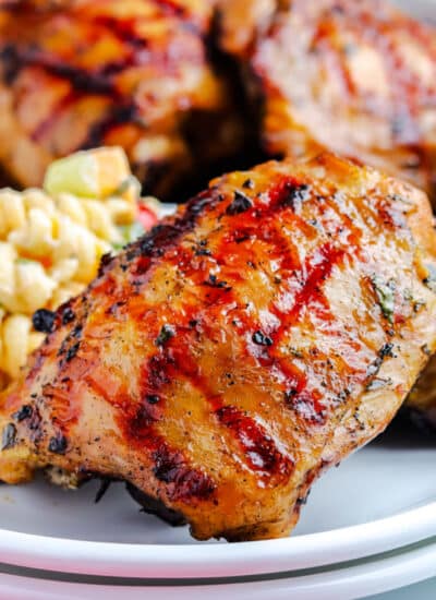a grilled chicken thigh on a plate with pasta salad