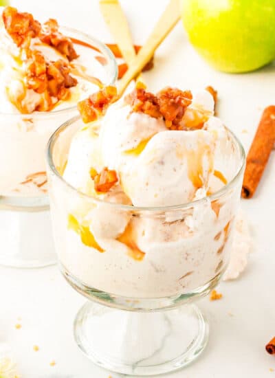 two glass dishes of apple pie ice cream with apples in the background