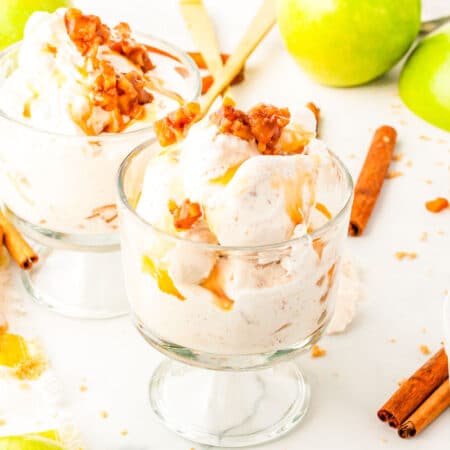 two glass dishes of apple pie ice cream with apples in the background