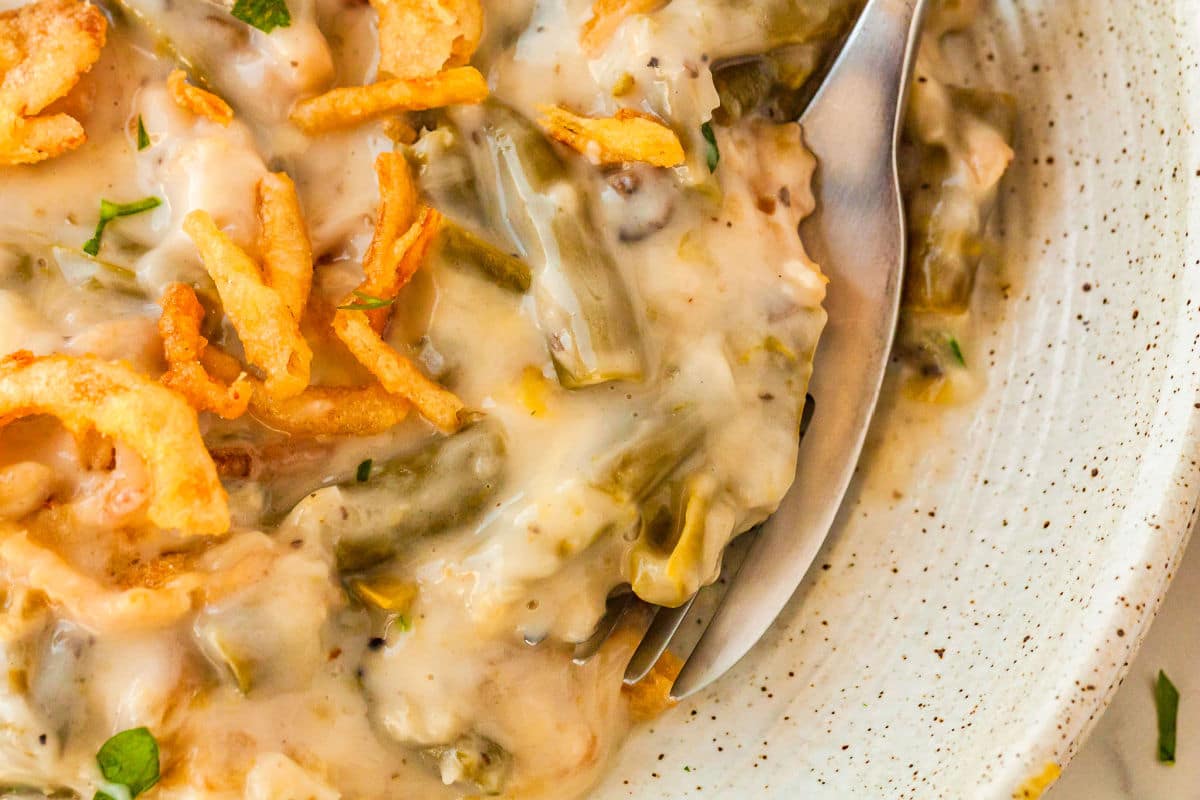 a close up of green bean casserole on a plate with a fork