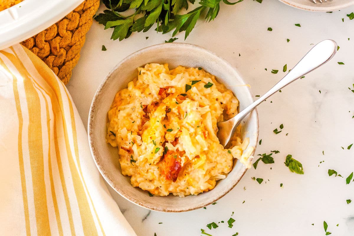 a white bowl with a spoon and hashbrown casserole