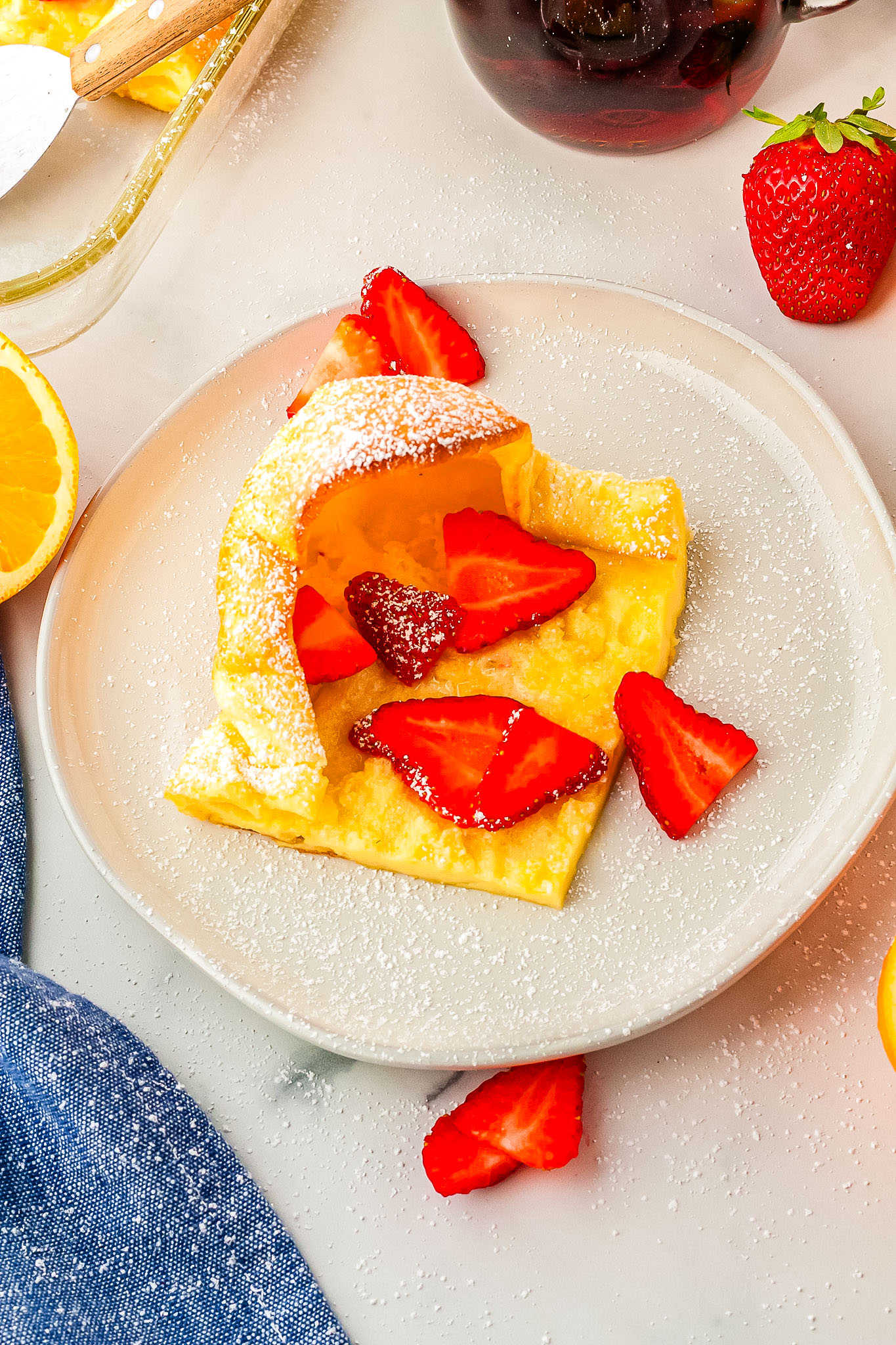 a plate with a slice of German pancakes and strawberries on it