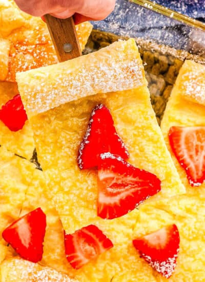 a baking dish with German pancakes with strawberries on it and one slice on a spatula