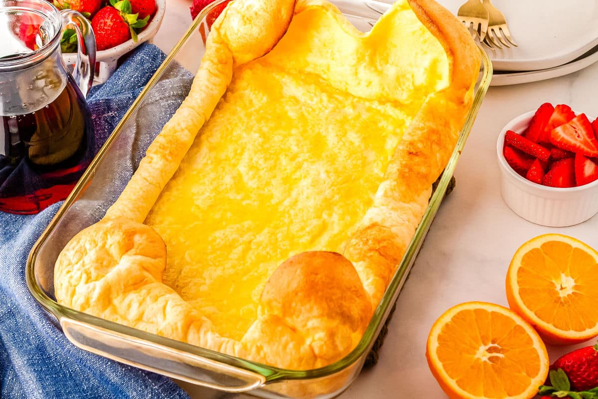 a baking dish of puff pancakes with oranges on the side
