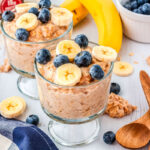kodiak oatmeal in two parfait glasses with fruit on top and serving spoons on the side