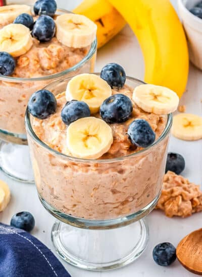 kodiak oatmeal in two parfait glasses with fruit on top and serving spoons on the side