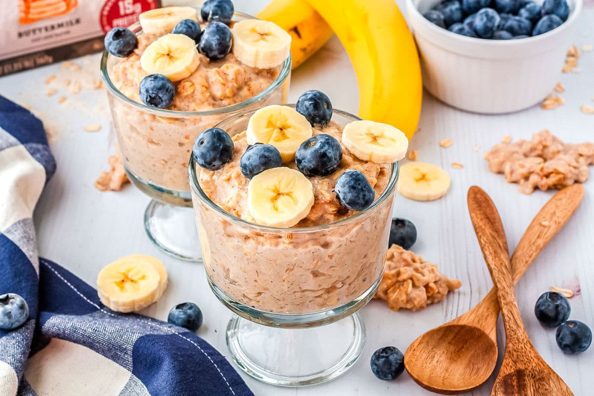 kodiak oatmeal in two parfait glasses with fruit on top and serving spoons on the side